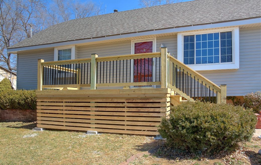 A house with a wooden deck and stairs in front of it.