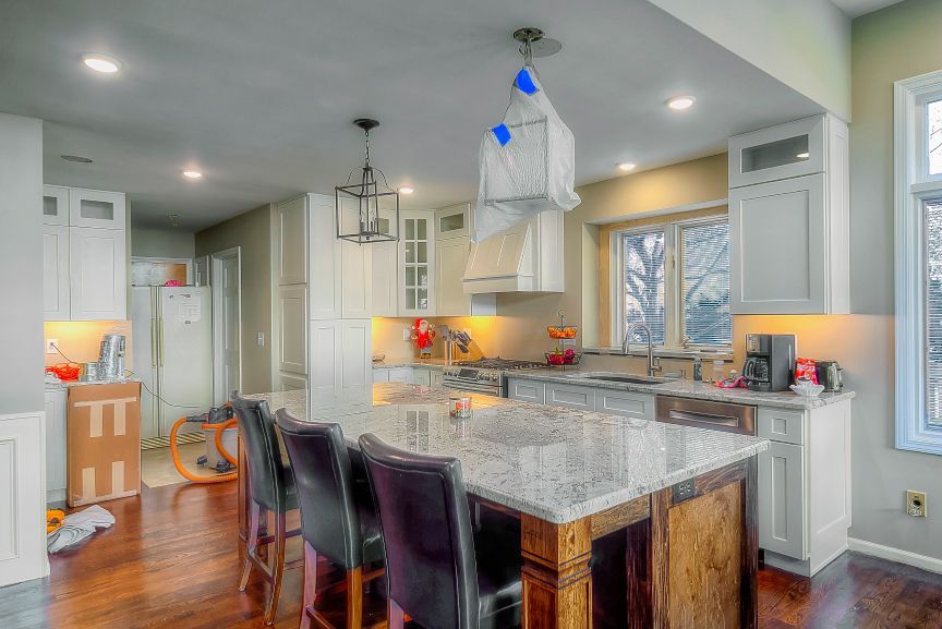 A kitchen with white cabinets , granite counter tops , and a large island.