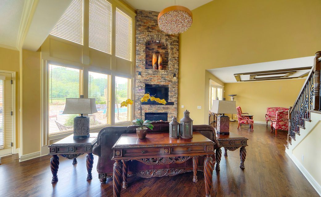 A living room with a fireplace , table , chairs and stairs.