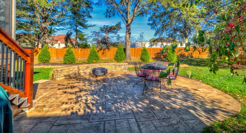 A patio with a table and chairs and a fire pit in the backyard of a house.