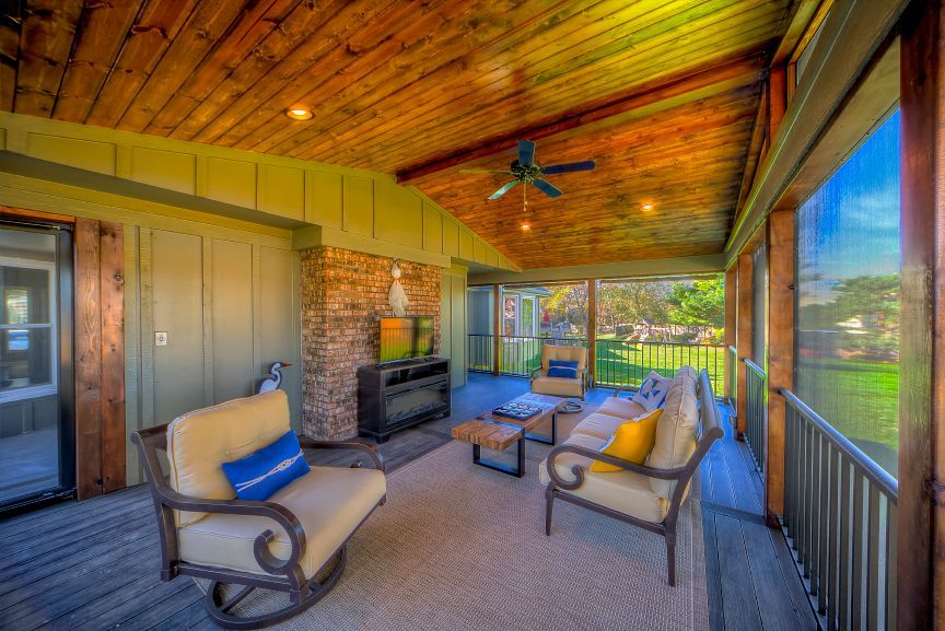 A screened in porch with furniture and a fireplace.