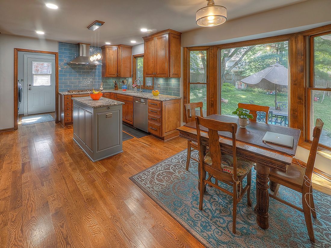 A kitchen with a dining table and chairs and a large window.