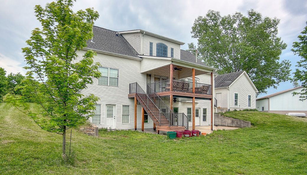 A large white house is sitting on top of a grass covered hill.