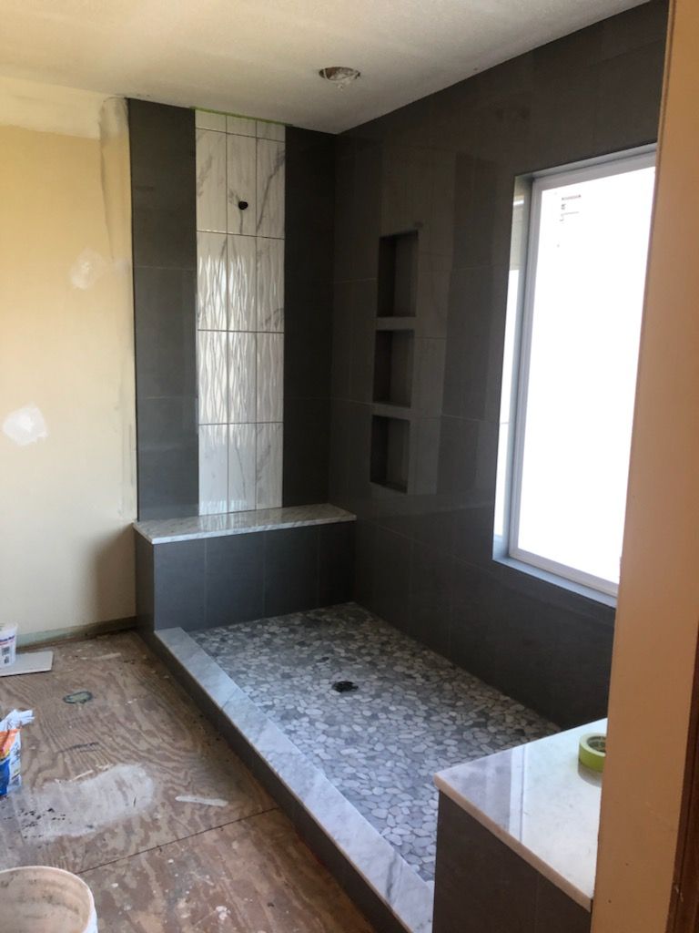 A bathroom with a walk in shower and a window.