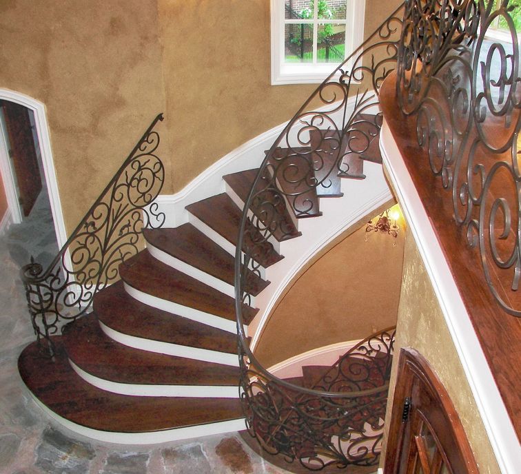A wooden spiral staircase with a wrought iron railing