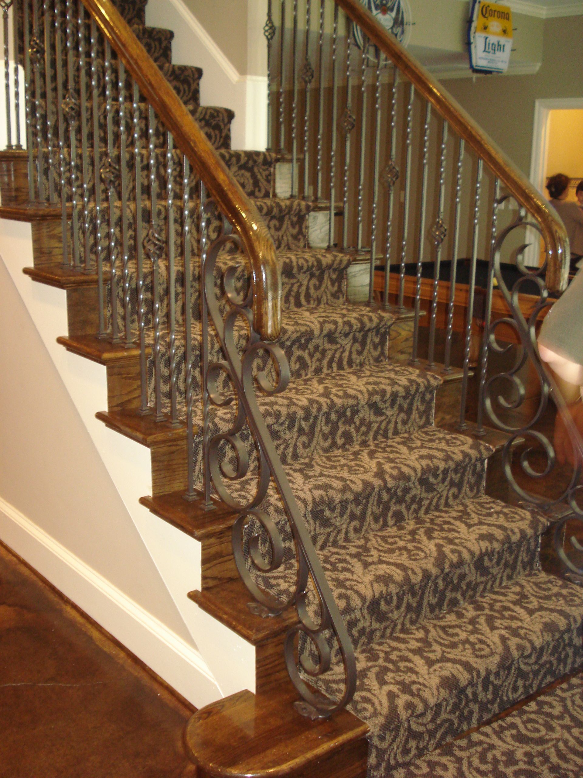 A staircase with a wrought iron railing and a carpeted floor