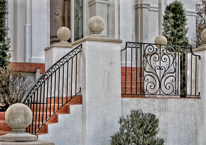 A white building with stairs and a wrought iron railing
