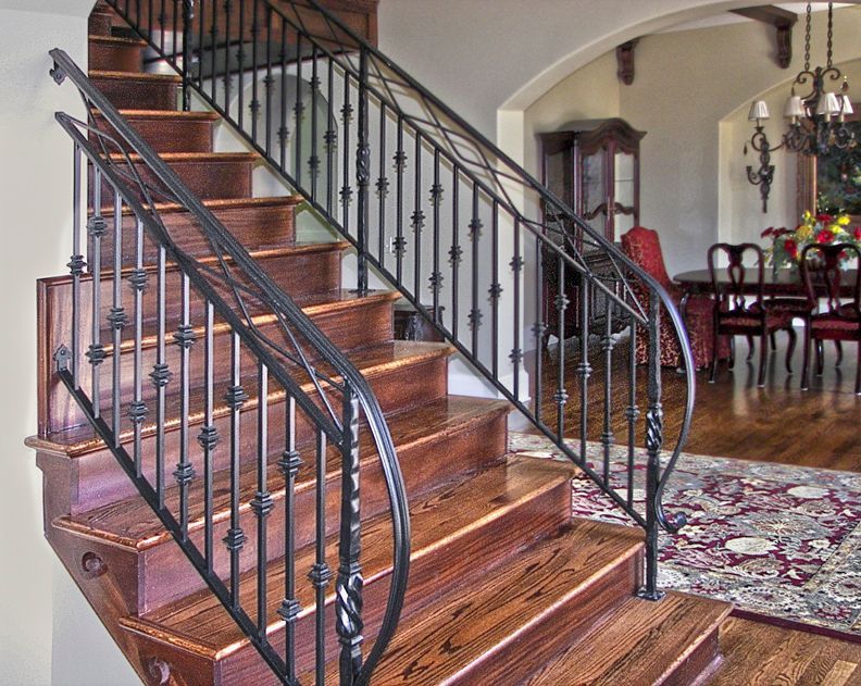 A wooden staircase with a wrought iron railing