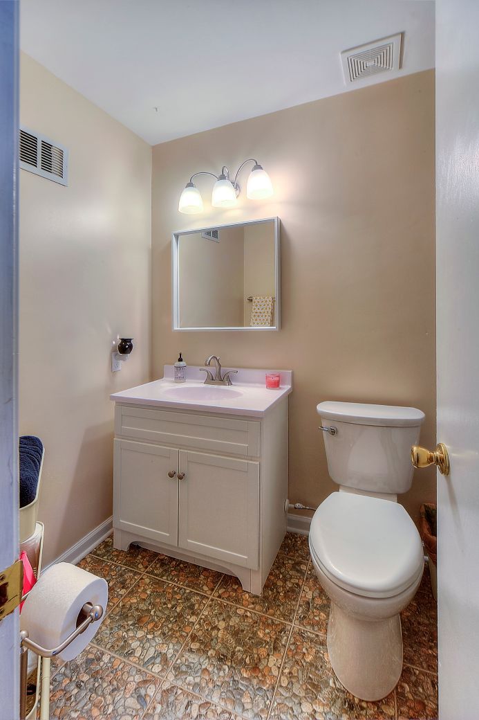 A bathroom with a toilet , sink and mirror.