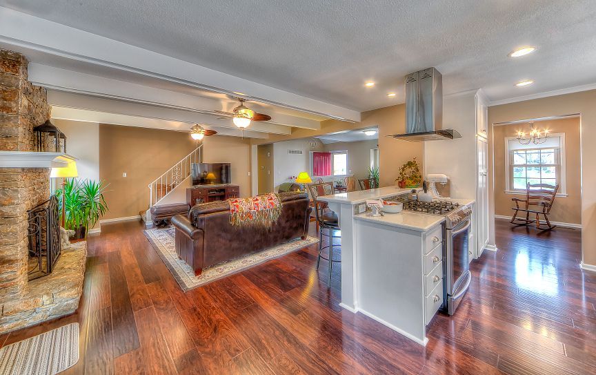 A living room and kitchen in a house with hardwood floors.