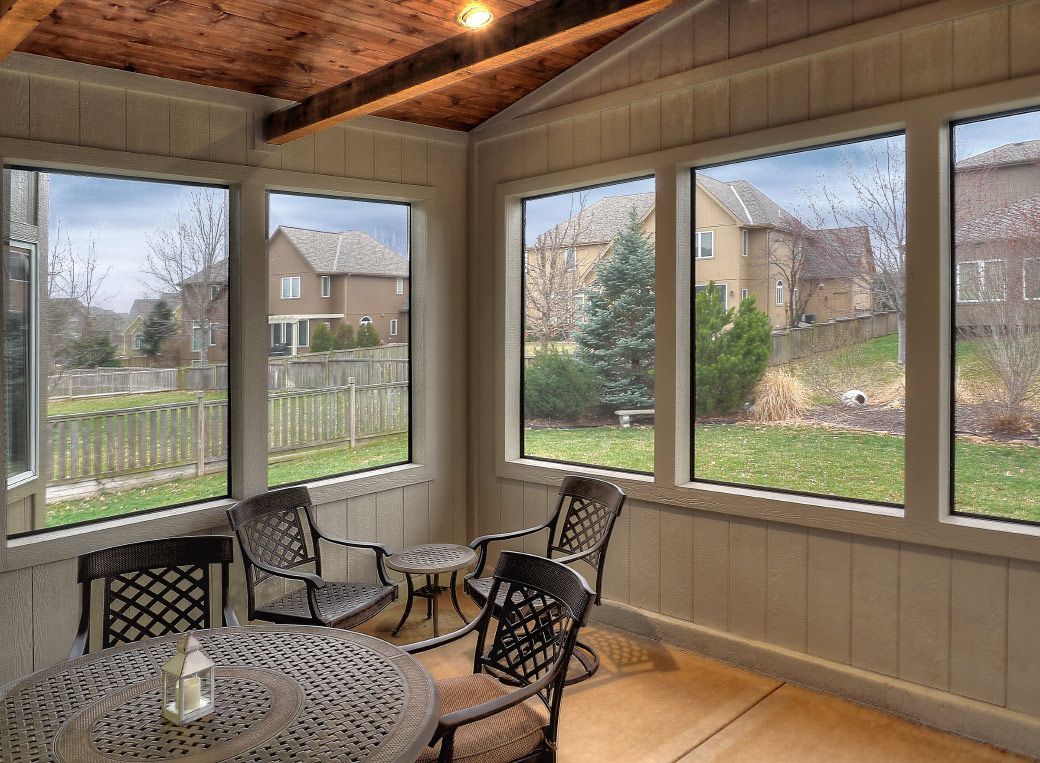 A screened in porch with a table and chairs and lots of windows.
