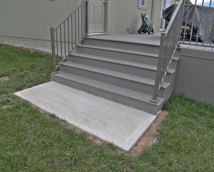 A set of stairs leading up to a deck with a metal railing.