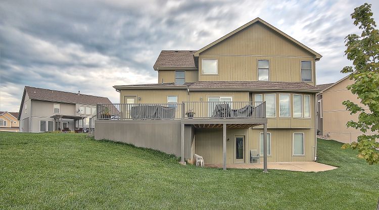 The back of a large house with a large deck.