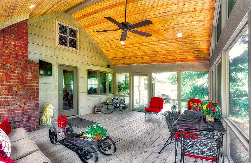 A screened in porch with a table and chairs and a ceiling fan.