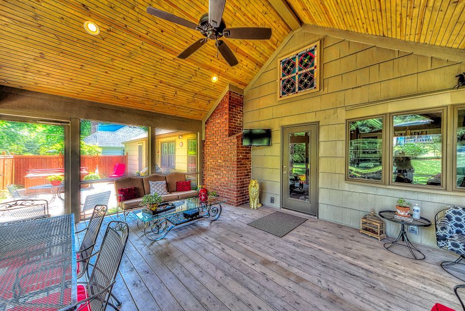 A screened in porch with a ceiling fan and a lot of furniture.