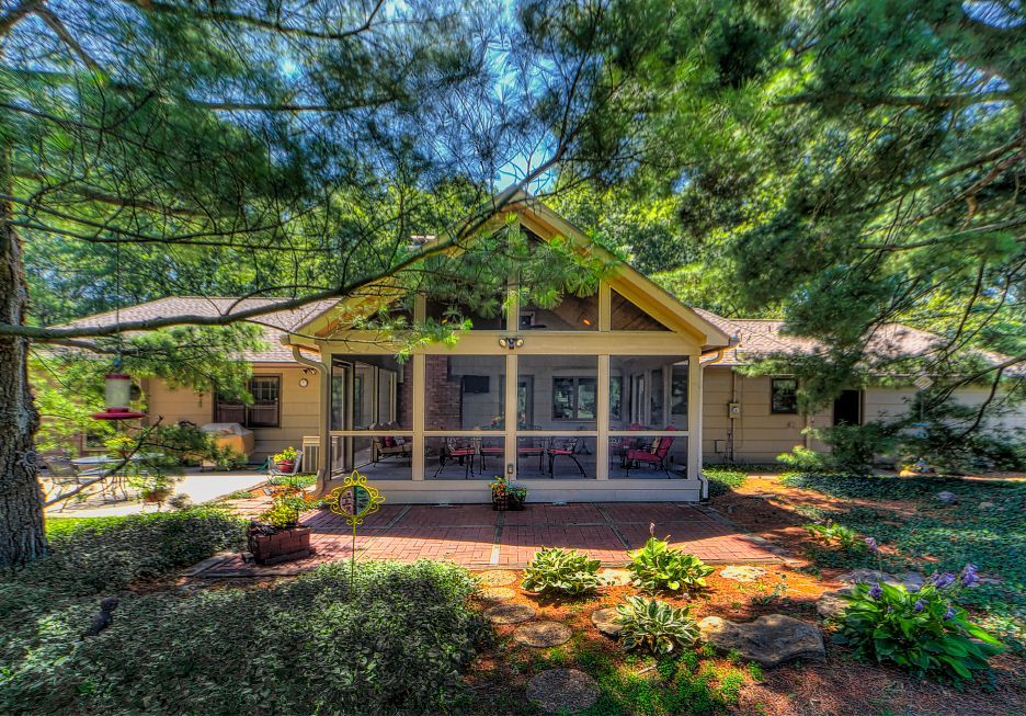 A house with a screened in porch surrounded by trees.