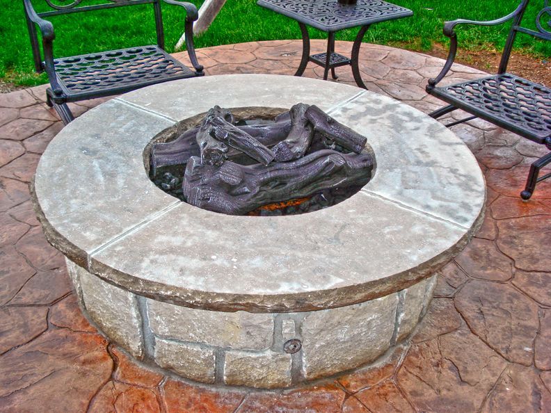 A fire pit is surrounded by chairs and a table.