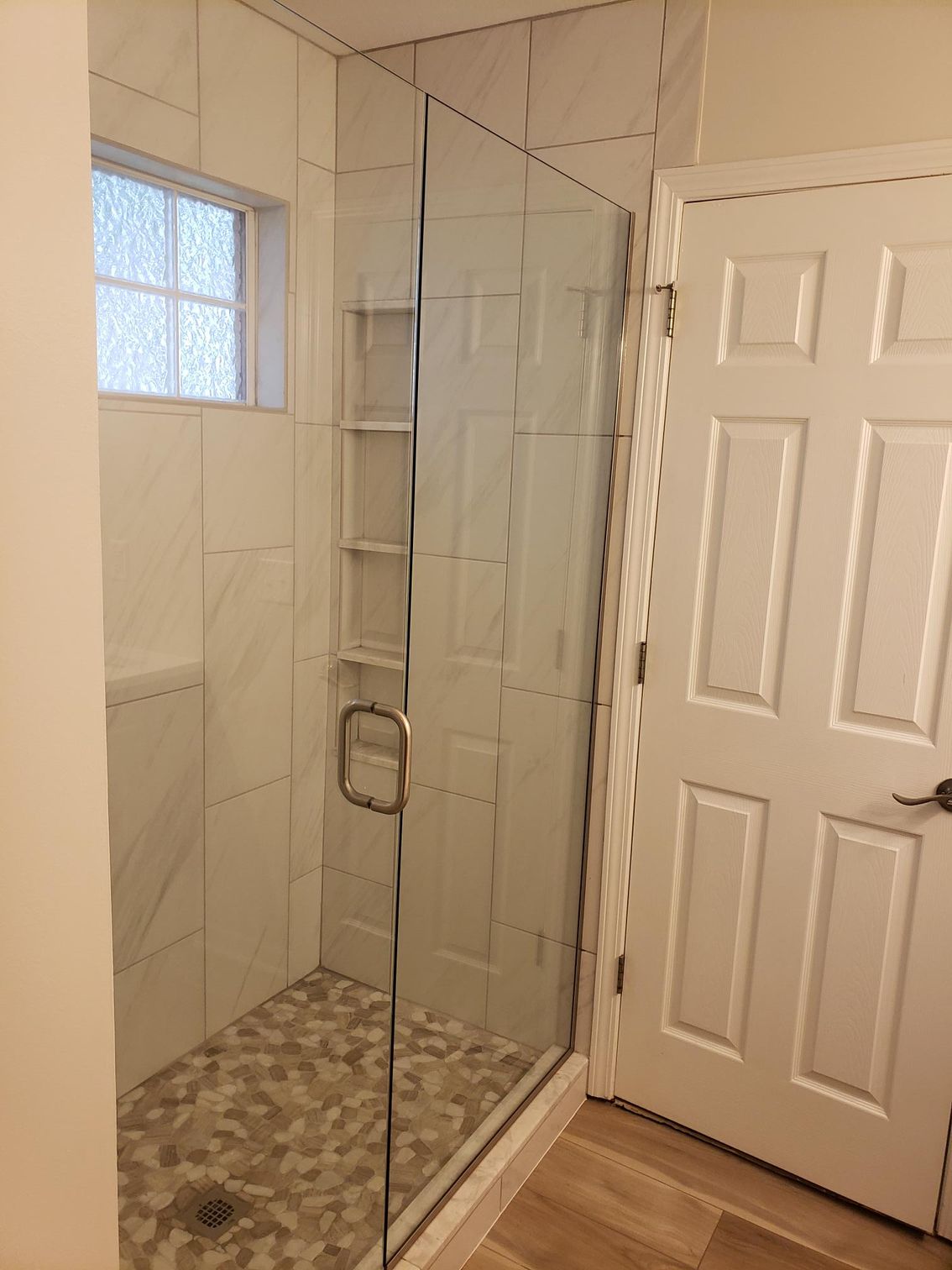 A bathroom with a walk in shower and a door.