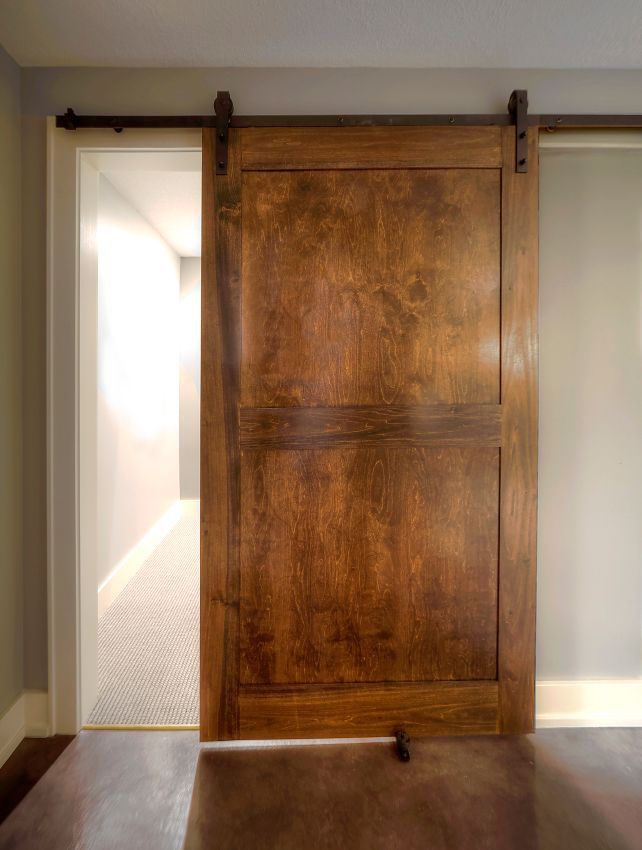 A wooden sliding barn door is open in a room.