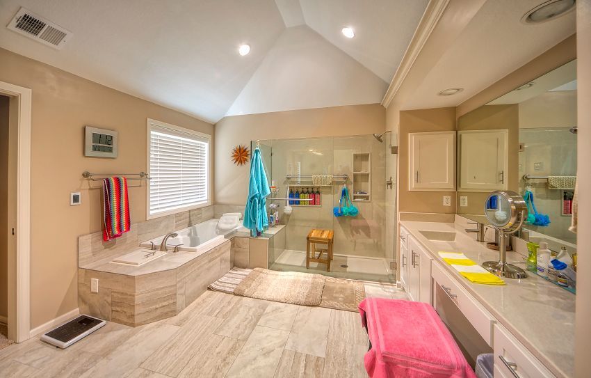 A bathroom with two sinks , a tub , and a walk in shower.