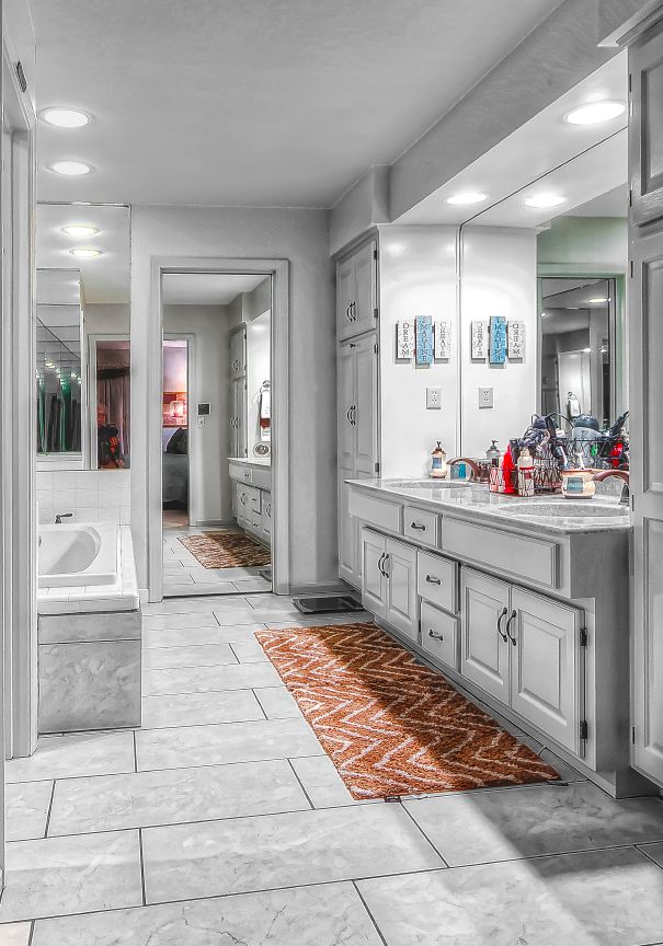A bathroom with two sinks , a tub , and a mirror.