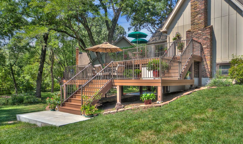 A large wooden deck with stairs and umbrellas in front of a house.