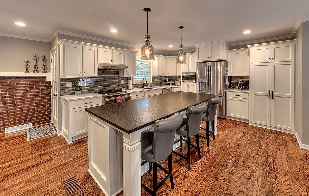 A kitchen with white cabinets , granite counter tops , stainless steel appliances , and hardwood floors.