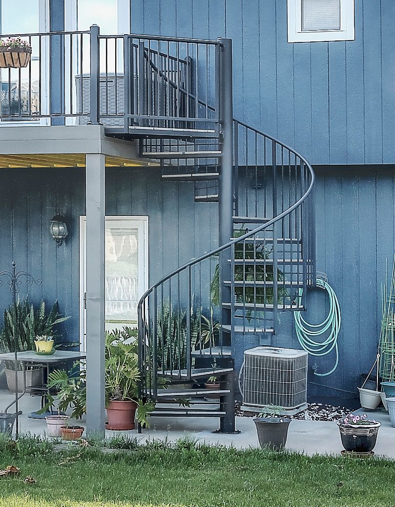 A blue house with a spiral staircase on the side