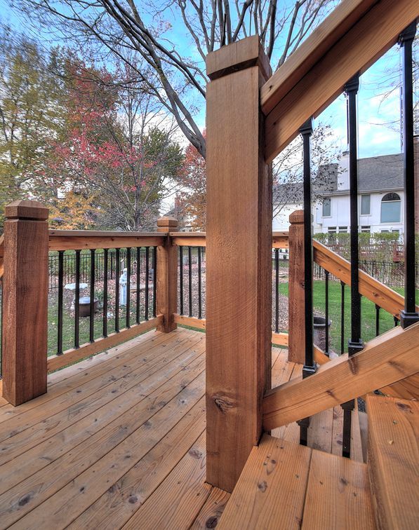 A wooden deck with black railing and stairs