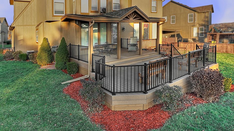 A house with a large deck and a fence in front of it.