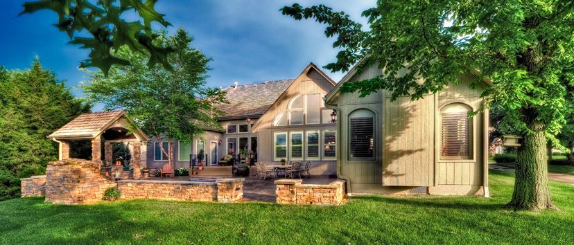 A large house with a lot of windows is surrounded by trees and grass.