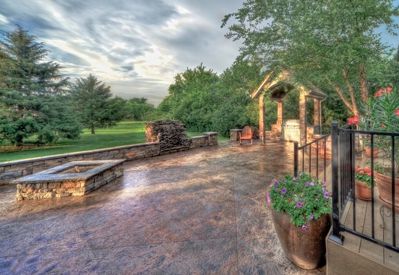 A patio with a fire pit and a gazebo in the background.