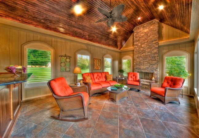 A living room with a couch , chairs , a fireplace and a ceiling fan.
