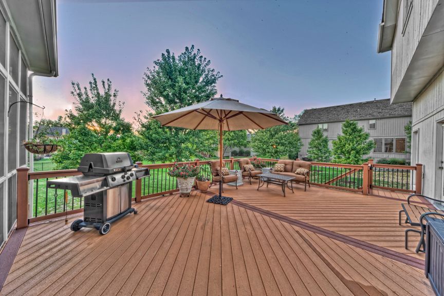 A large wooden deck with a grill and umbrella.