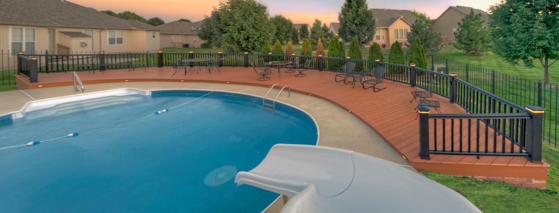 There is a swimming pool with a slide in the backyard.