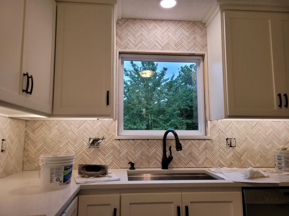 A kitchen with white cabinets and a stainless steel sink