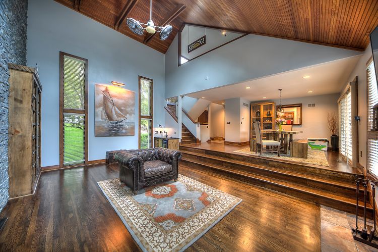 A living room with hardwood floors , stairs , a chair and a rug.