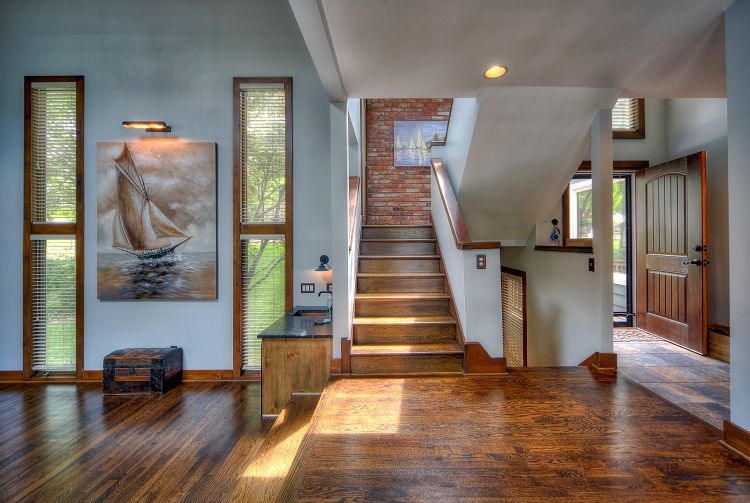 A hallway with stairs and a painting of a sailboat on the wall