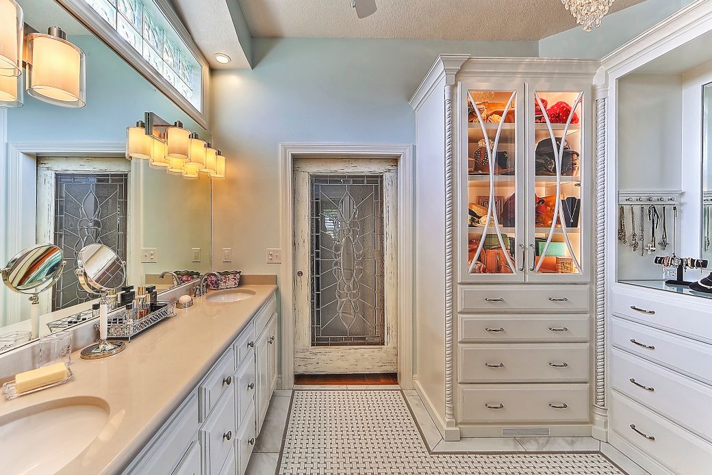 A bathroom with two sinks , a mirror and a walk in closet.