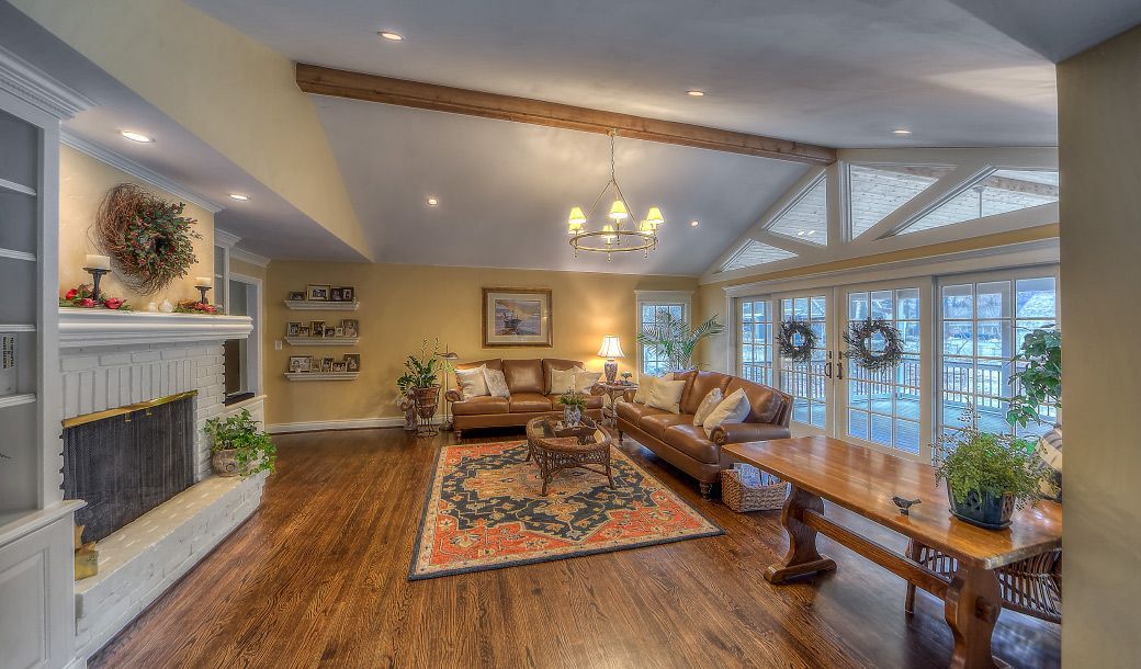 A living room with hardwood floors , a fireplace , a couch and a table.