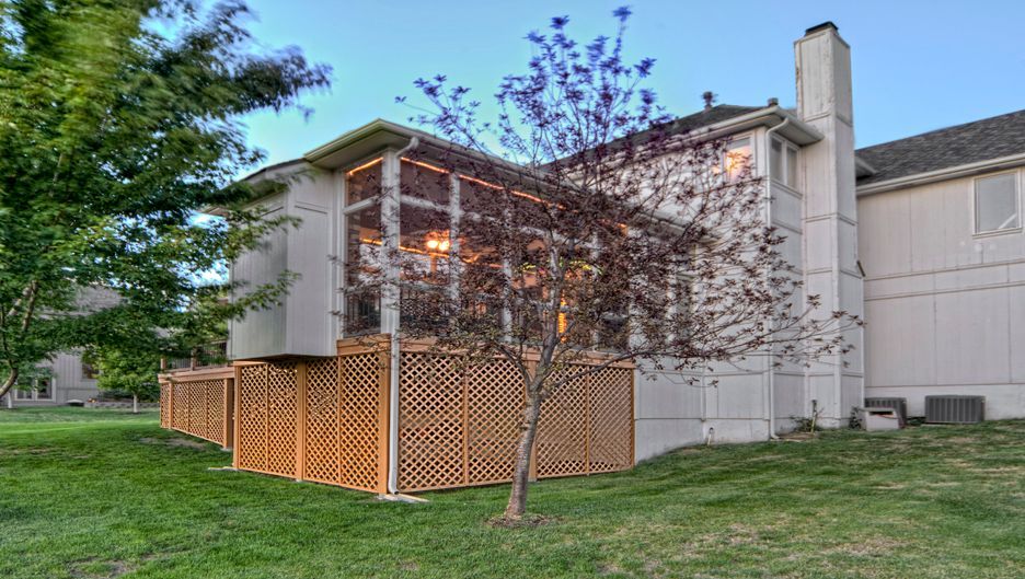 A house with a screened in porch and a tree in front of it.