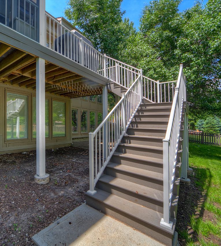 A set of stairs leading up to a deck with a white railing