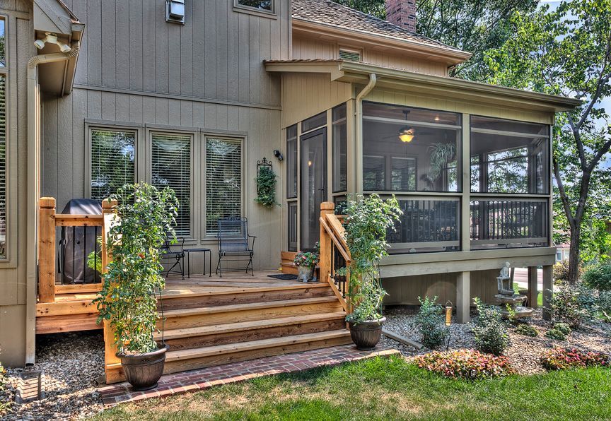 A house with a screened in porch and a wooden deck.