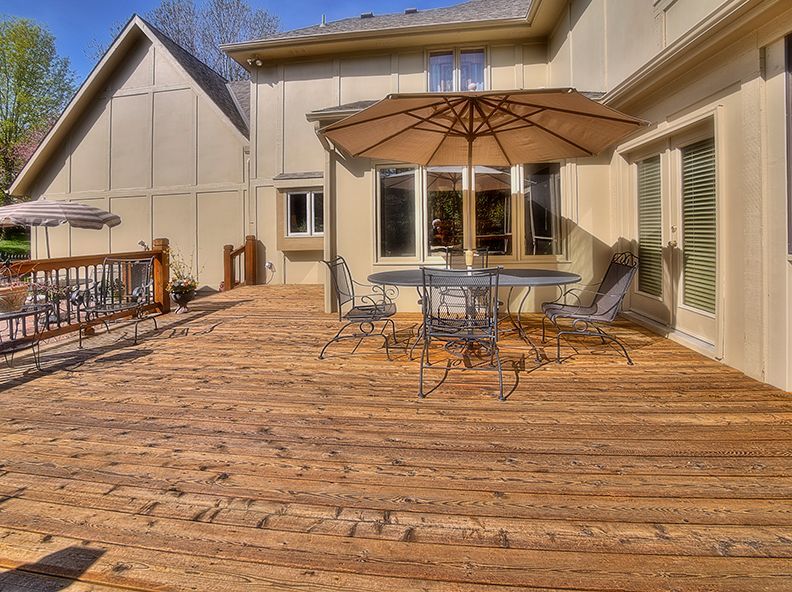 A wooden deck with a table and chairs and an umbrella