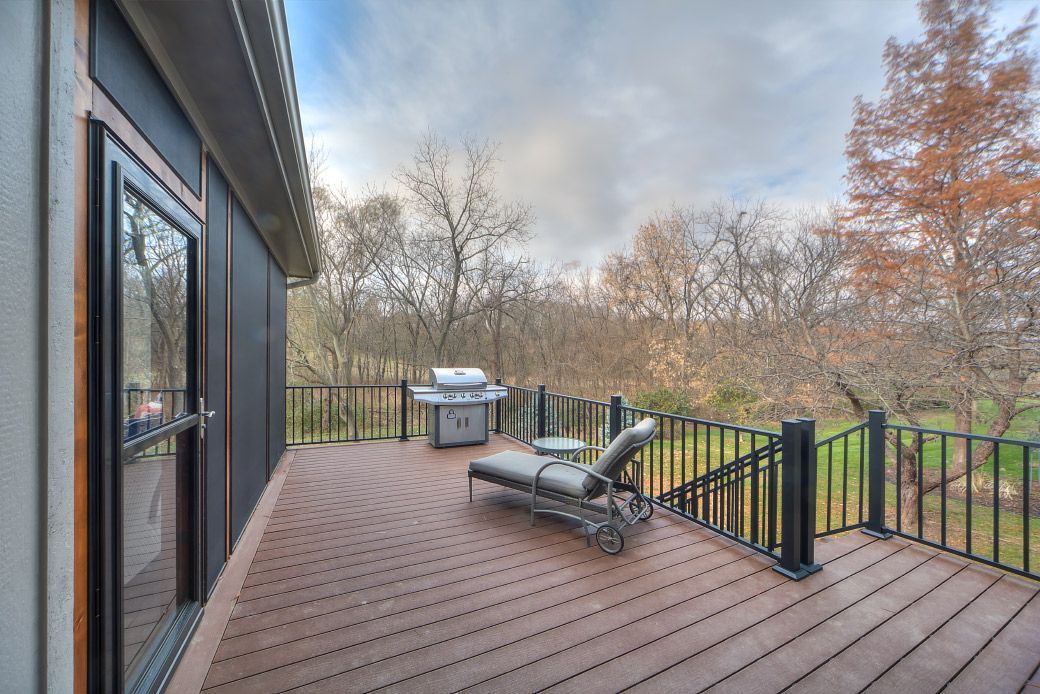 There is a deck with a grill and chairs on it.