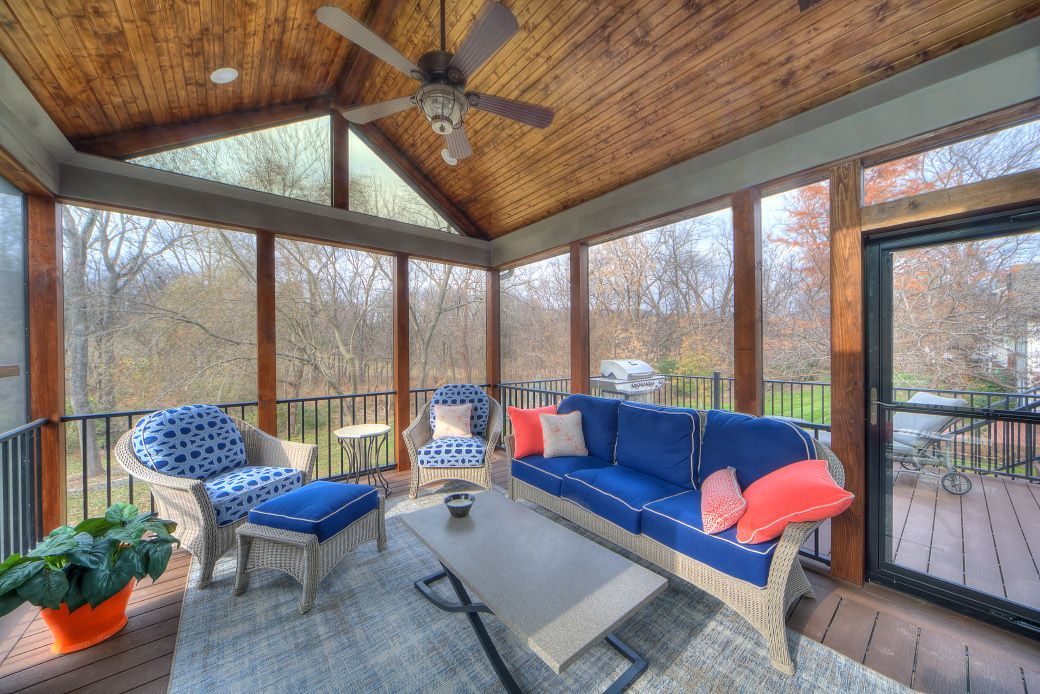 A screened in porch with a blue couch and chairs