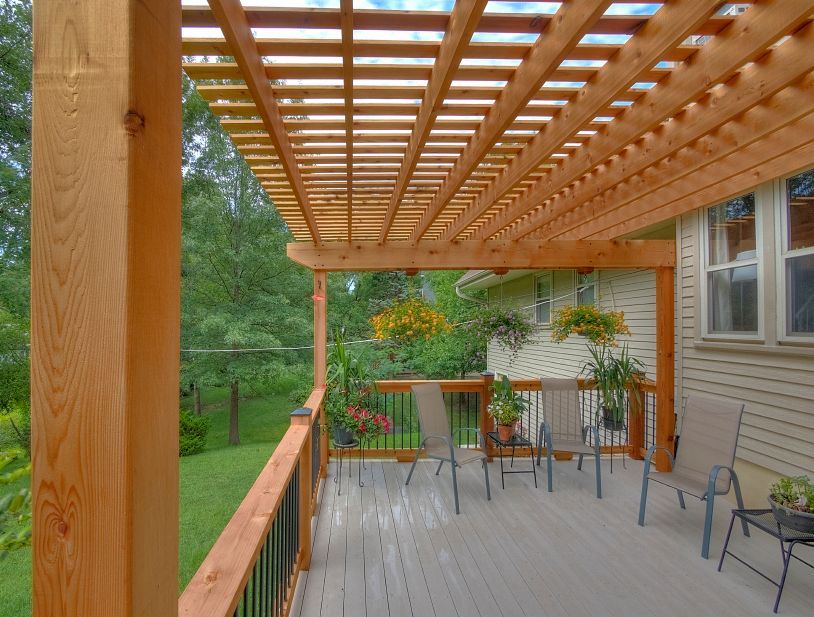 A wooden deck with a pergola and chairs on it