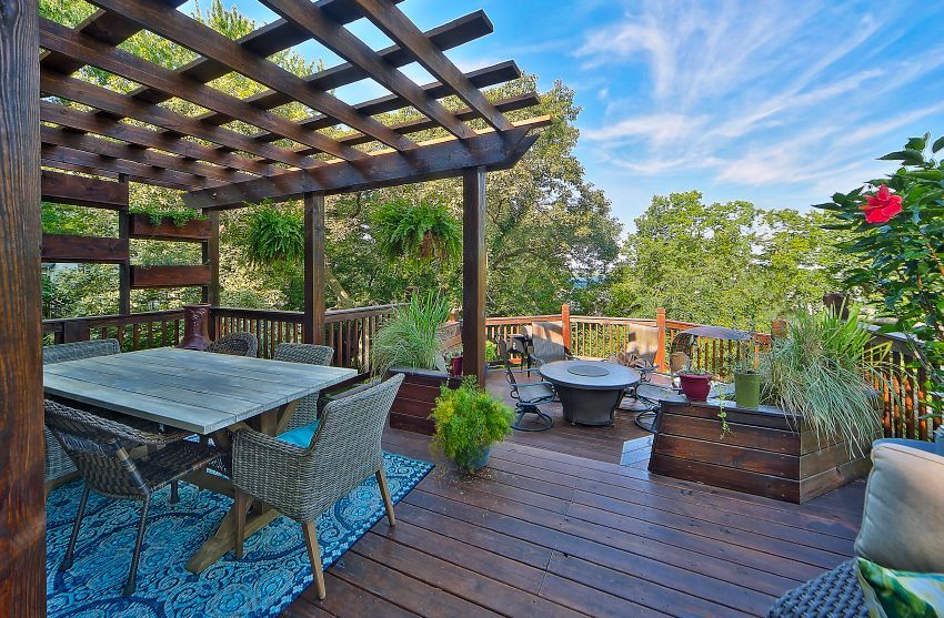 A wooden deck with a table and chairs under a pergola.