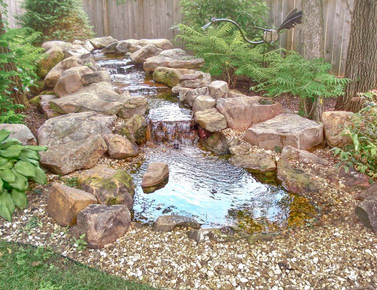 There is a waterfall in the middle of the garden surrounded by rocks.