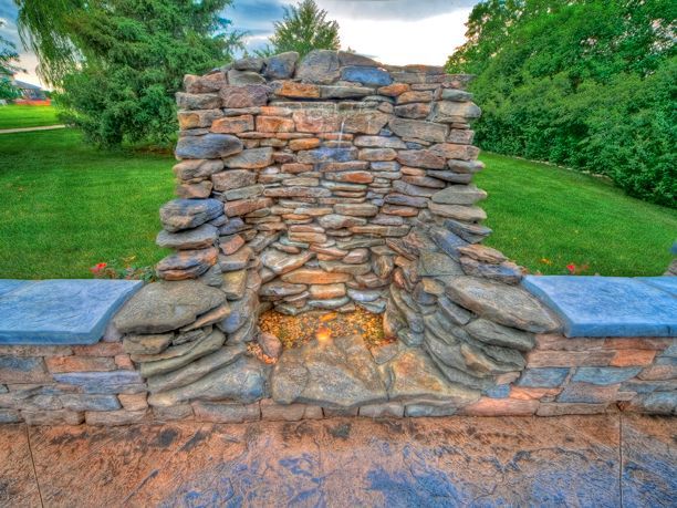 A stone wall with a waterfall in the middle of it